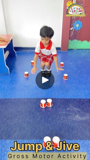 a young boy is playing with cups on the floor in front of his classroom desk