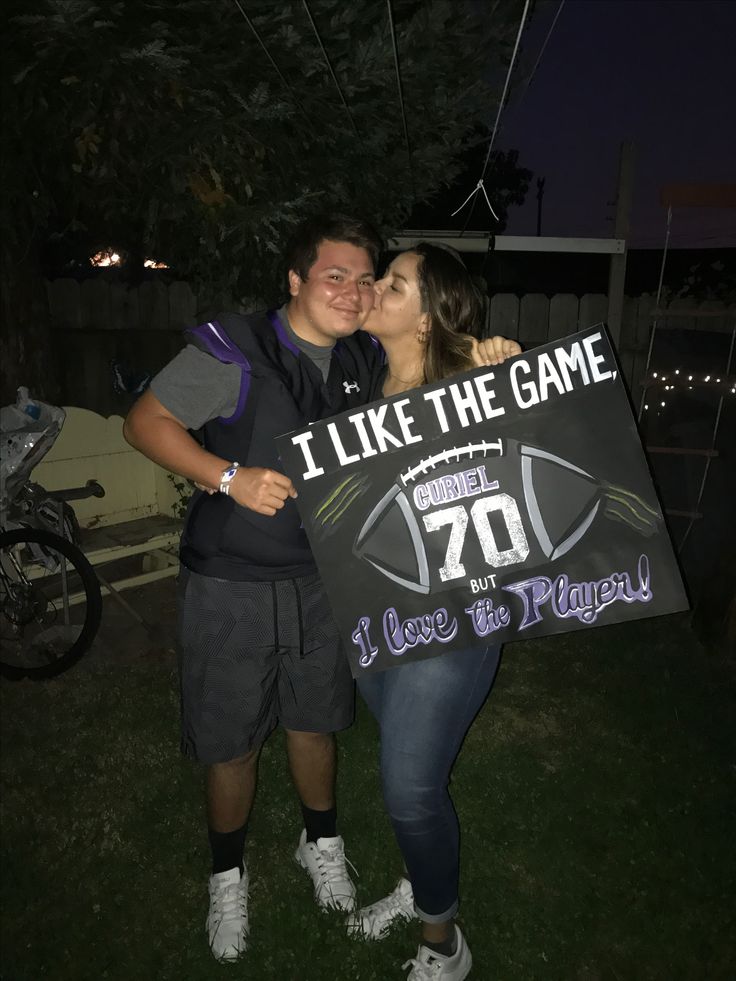 a man and woman are kissing while holding a sign that says i like the game