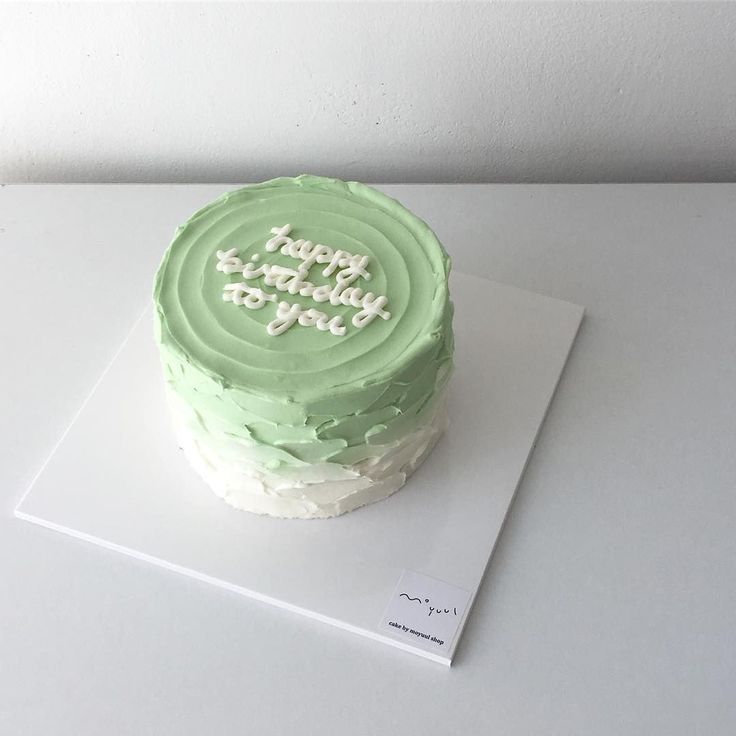 a green birthday cake sitting on top of a white table next to a sign that says happy birthday to you