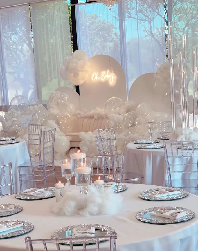 a table set up for a party with balloons and candles in the centerpieces