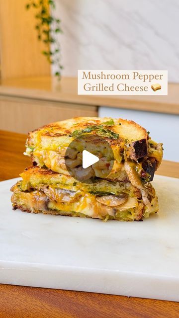 a grilled cheese sandwich on a cutting board with mushrooms and peppers in the middle