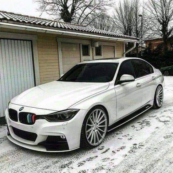 a white car parked in front of a house on a snow covered driveway with two garages