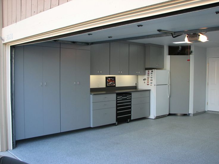 an open garage door shows the kitchen and living room in this apartment with gray cabinets