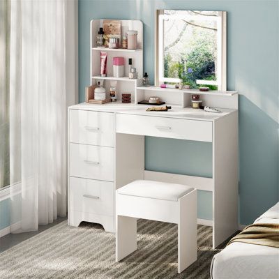 a white desk with drawers and a mirror in a blue room next to a bed