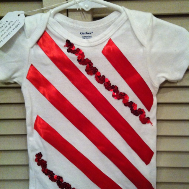 a red and white striped shirt with sequins on the chest is hanging from a hanger