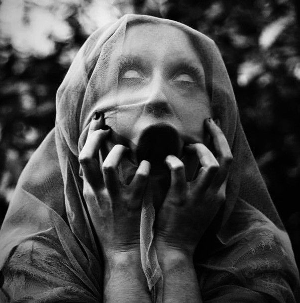 black and white photograph of a woman wearing a veil on her head talking on a cell phone