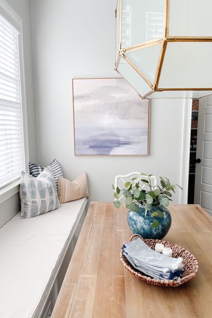 a wooden table topped with a blue vase filled with flowers next to a white couch