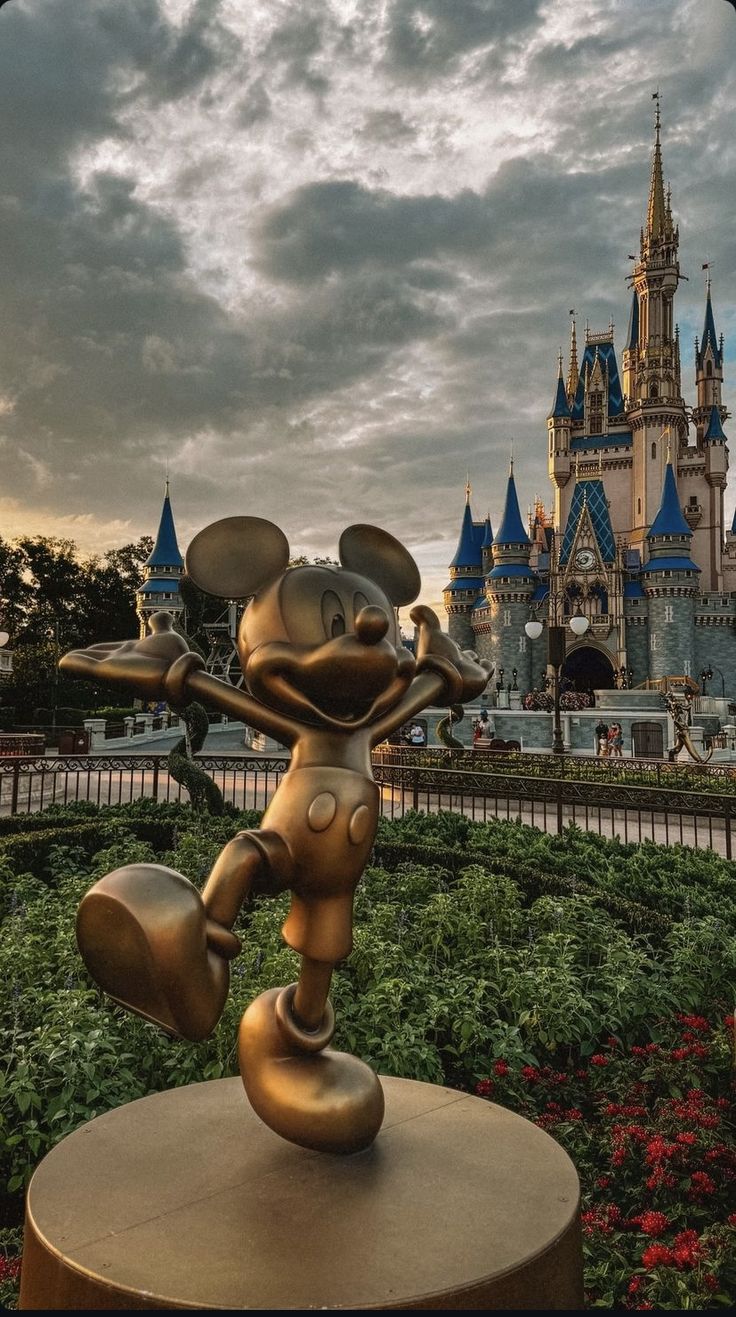 a statue of mickey mouse in front of a castle