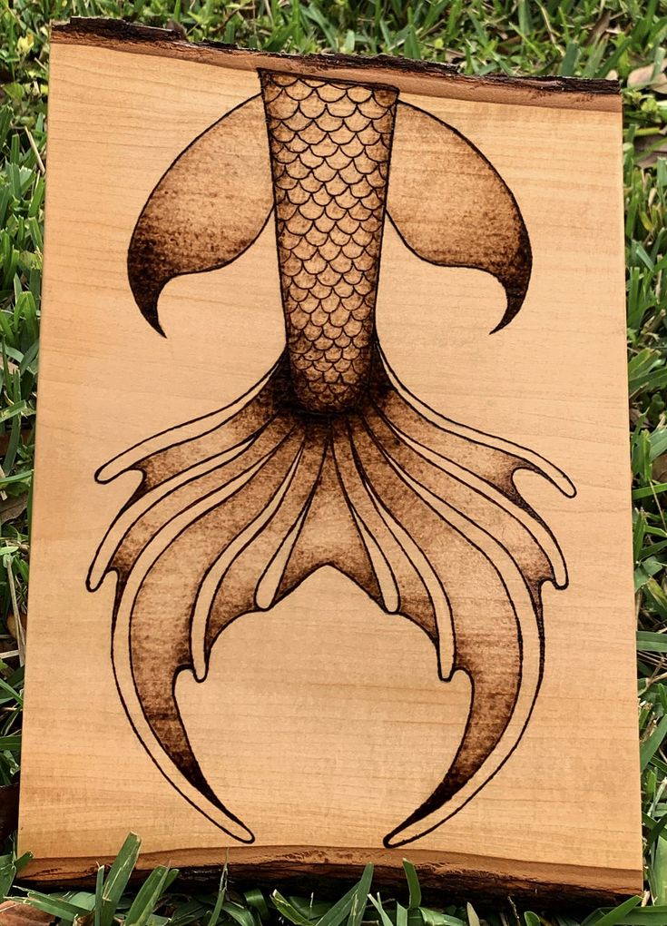 a wooden plaque with an image of a fish in the shape of a squid on it