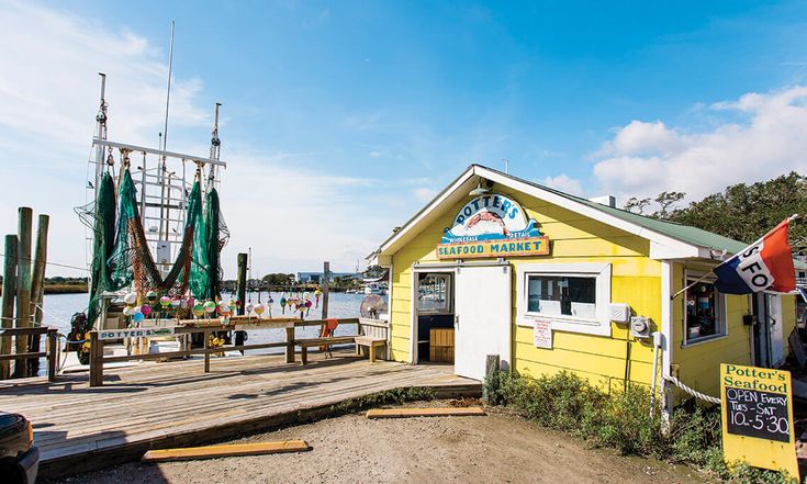 a small yellow building sitting next to a body of water with boats in the background