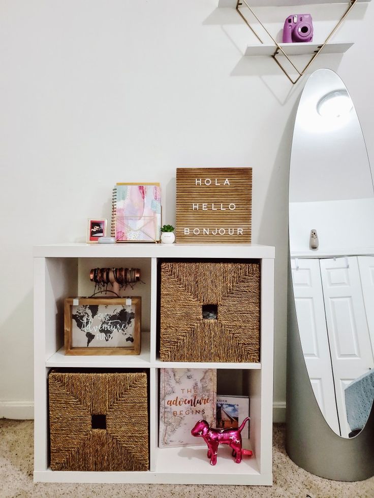 a white shelf with baskets on top of it next to a mirror and surfboard