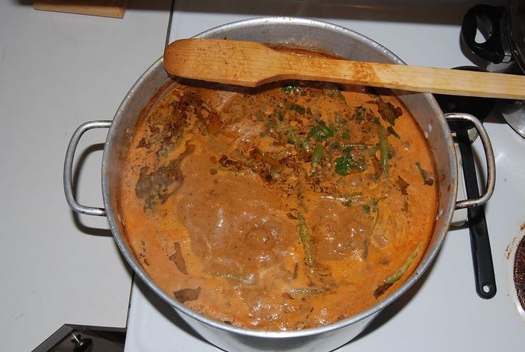 a pot filled with food sitting on top of a stove next to a wooden spoon