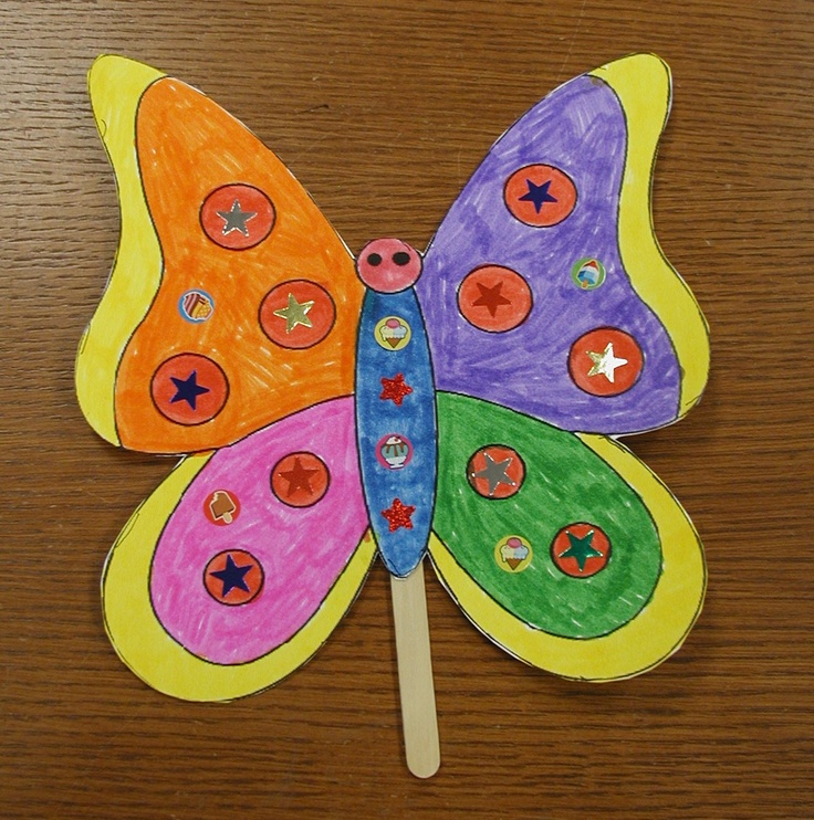 a colorful butterfly made out of paper on top of a wooden table next to a toothbrush