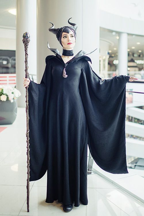 a woman dressed as maleficent holding a staff