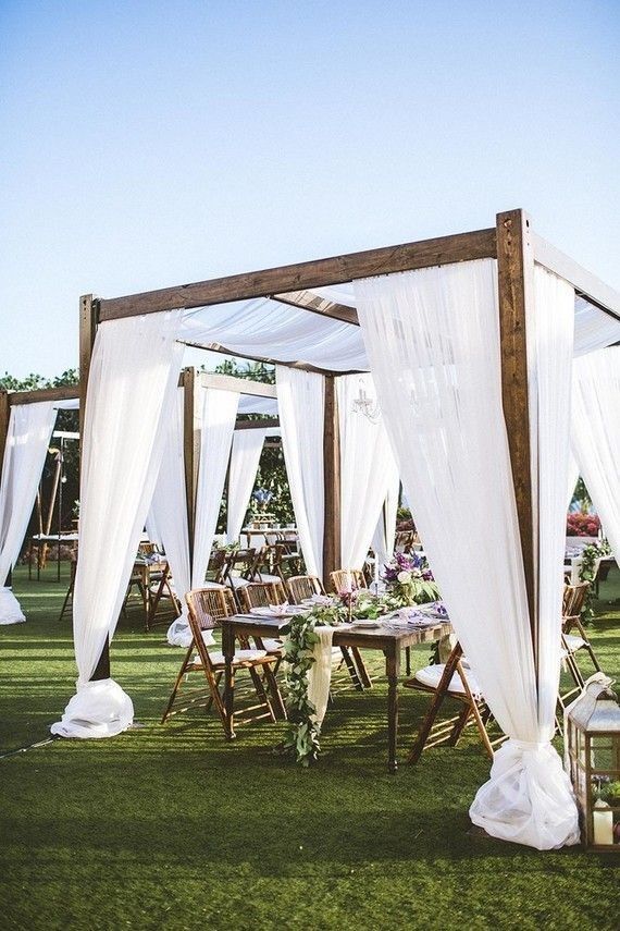 an outdoor wedding setup with white drapes and chairs