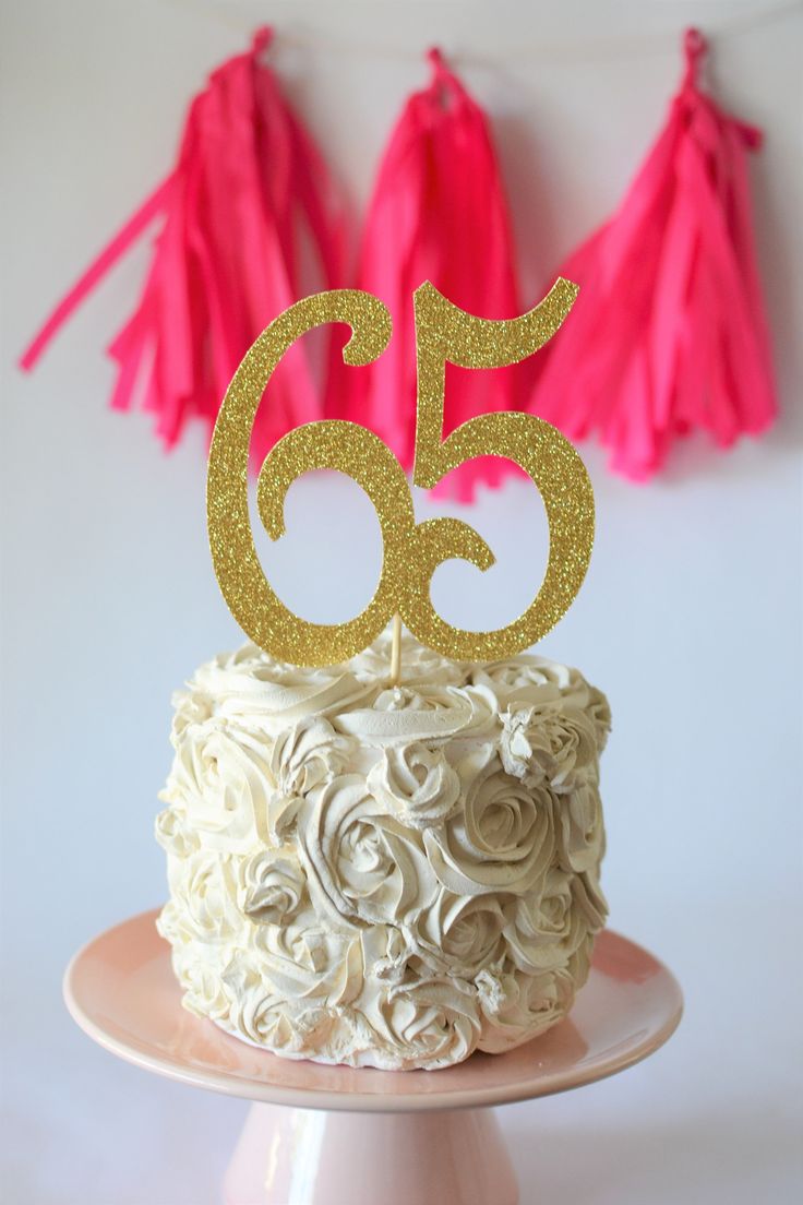 a cake with white frosting and gold numbers on top, sitting on a plate