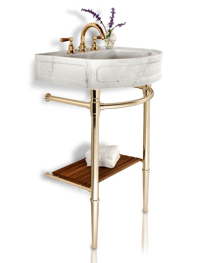 a bathroom sink with gold fixtures and a marble counter top, along with a wooden shelf for towels