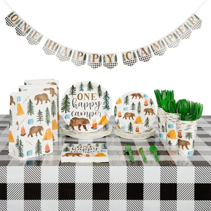 a table topped with plates and napkins covered in animal themed paper decorations next to a black and white checkered table cloth