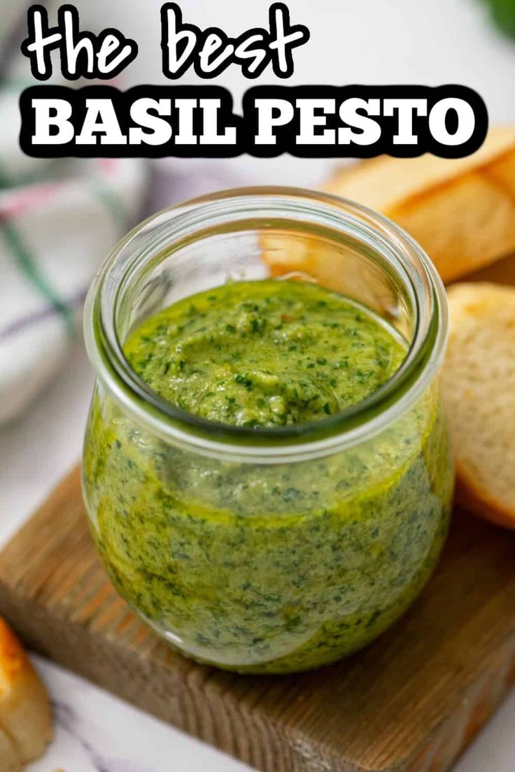 the best basil pesto in a glass jar on a cutting board next to bread