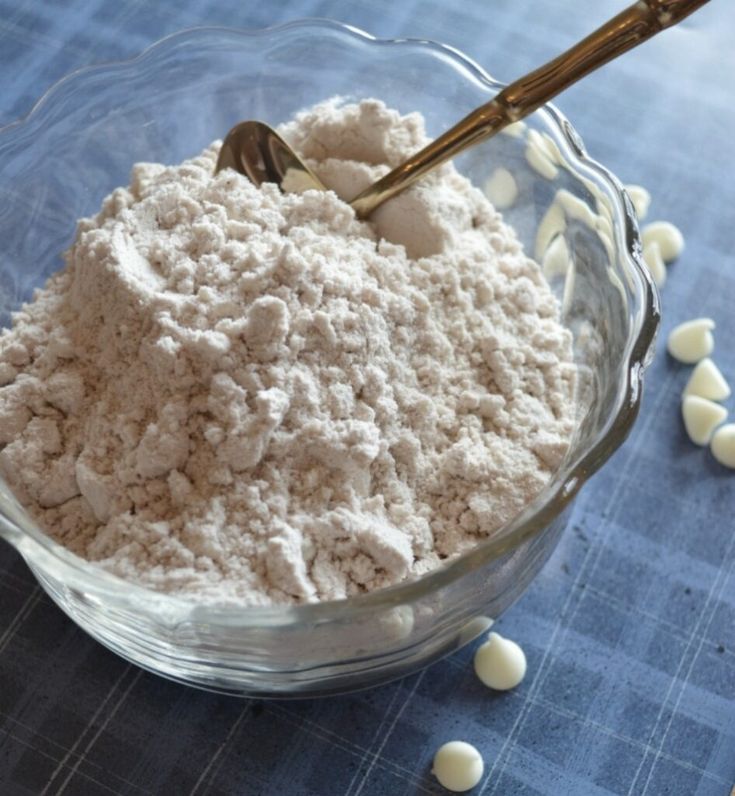 a glass bowl filled with white hot chocolate mix on top of a blue tablecloth