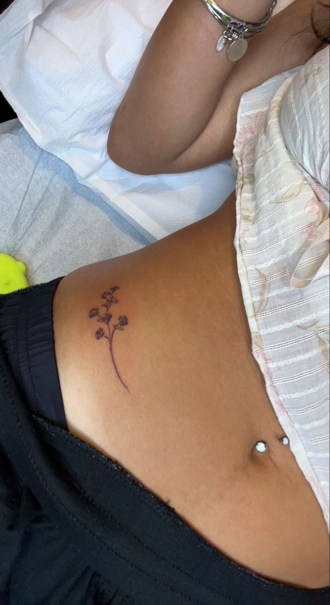 a woman's stomach with a small tattoo on her lower back, and a flower in the middle