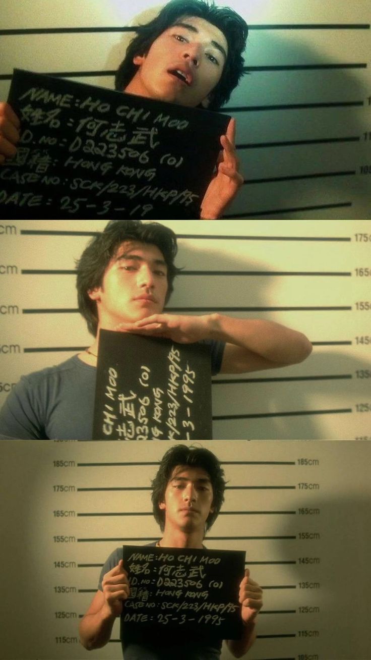 two men holding signs in front of their faces and behind them are mugshots