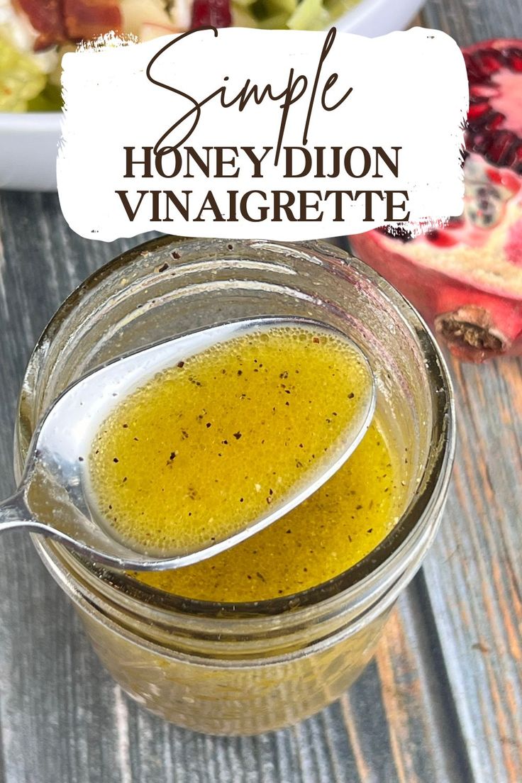 a jar filled with honey dijond vinaigrette on top of a wooden table