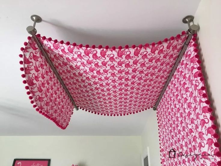 a pink and white crocheted bed spread hanging from the ceiling