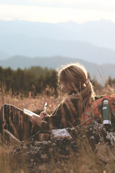 a woman sitting on top of a grass covered field