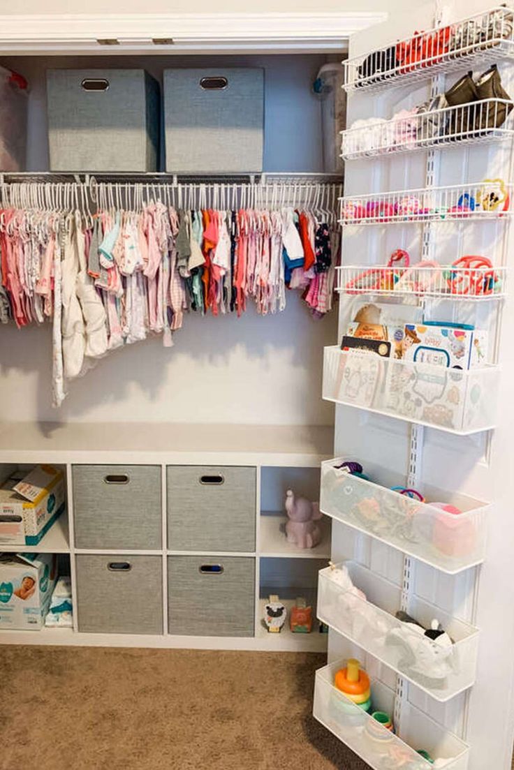 an organized closet with baby clothes and diapers hanging on the wall, along with storage bins