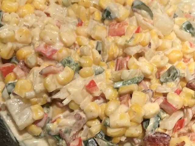 an uncooked pizza topped with corn and other veggie toppings in a pan