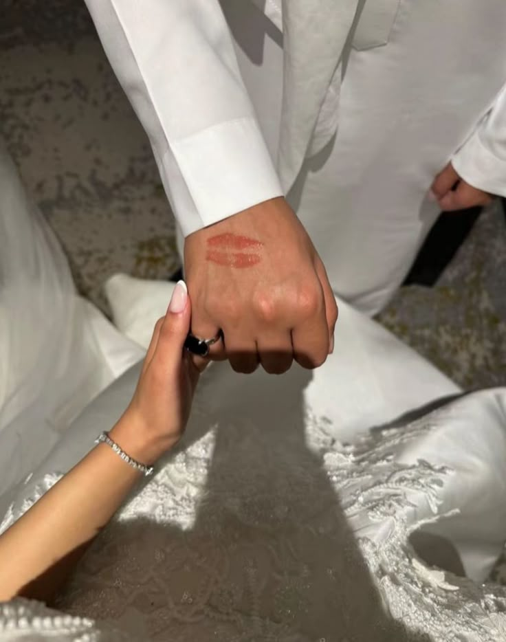 a man and woman holding hands while sitting on the ground in front of each other