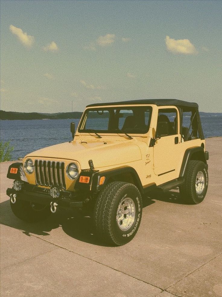 a yellow jeep parked next to the ocean