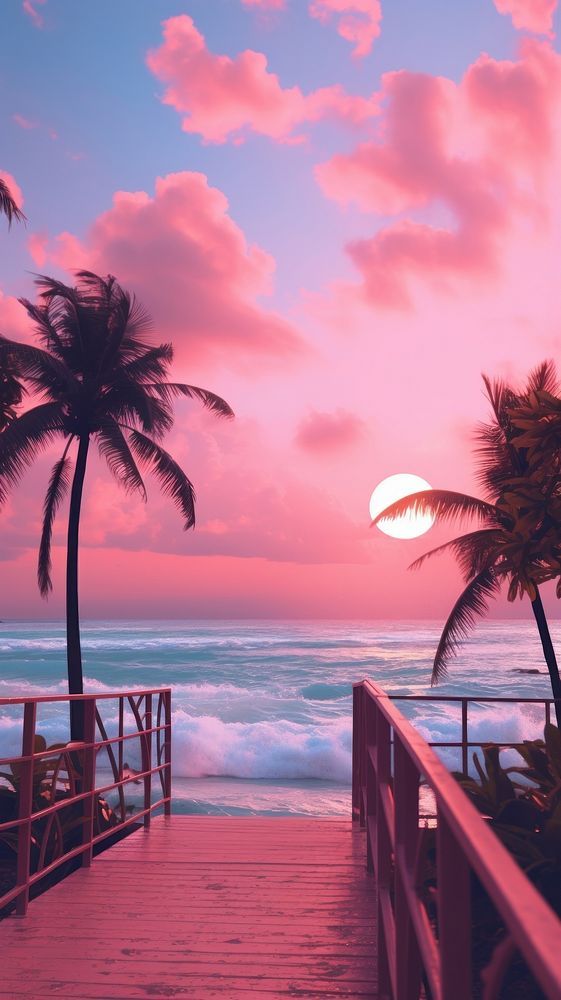 a wooden walkway leading to the beach with palm trees on either side and pink sunset in the background