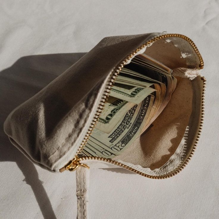 a purse filled with money sitting on top of a bed