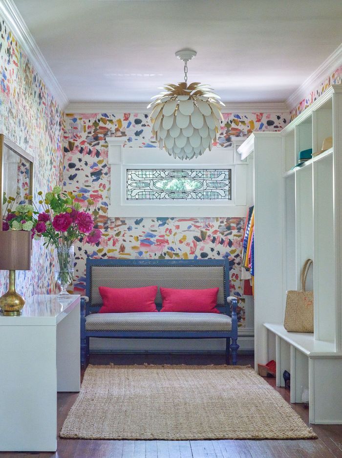 a living room filled with furniture and flowers on the wall next to a shelf full of books