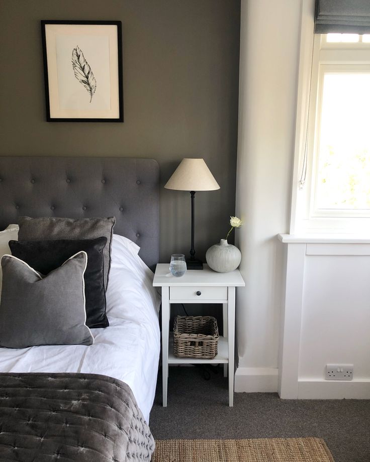 a bed sitting next to a window with a lamp on top of the headboard