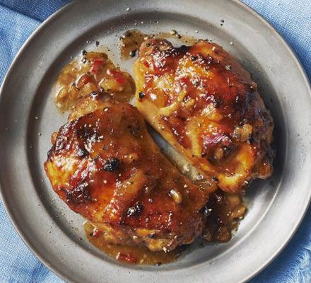 two pieces of chicken in a pan on a blue cloth next to a knife and fork