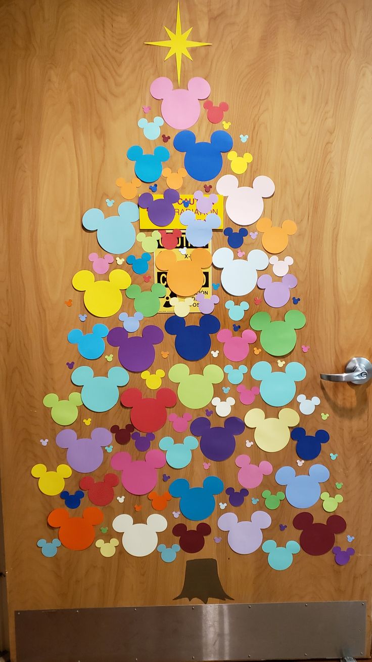 a christmas tree made out of mickey mouse cut outs is displayed in front of a wooden door