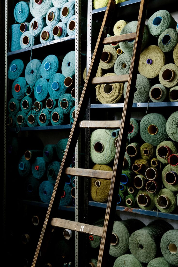 several rows of different colored spools of yarn are on shelves in a store