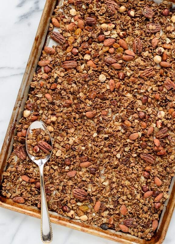 a baking pan filled with granola on top of a marble counter next to a spoon