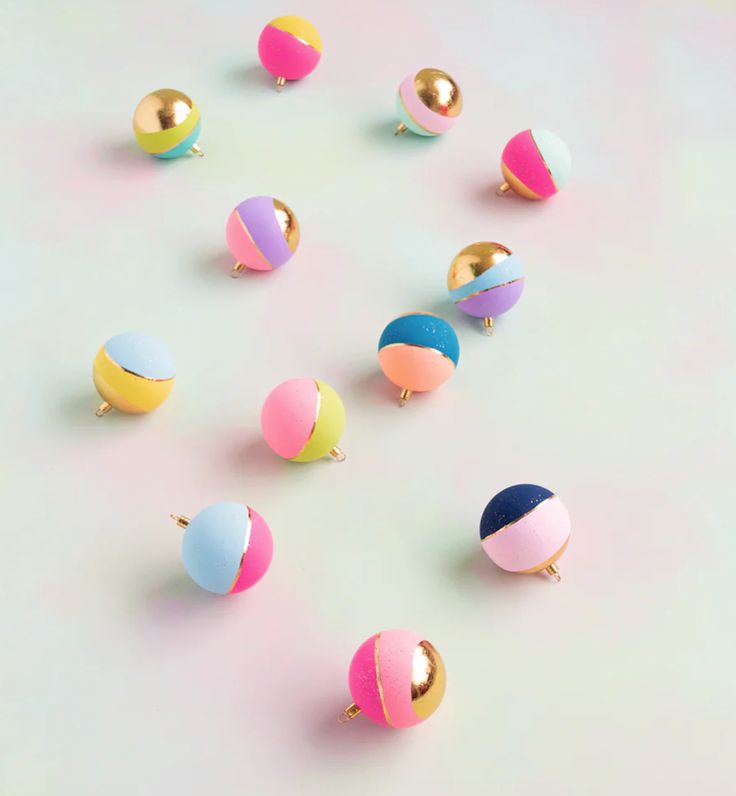 there are many different colored balls in the shape of an egg on a table with pink and blue background