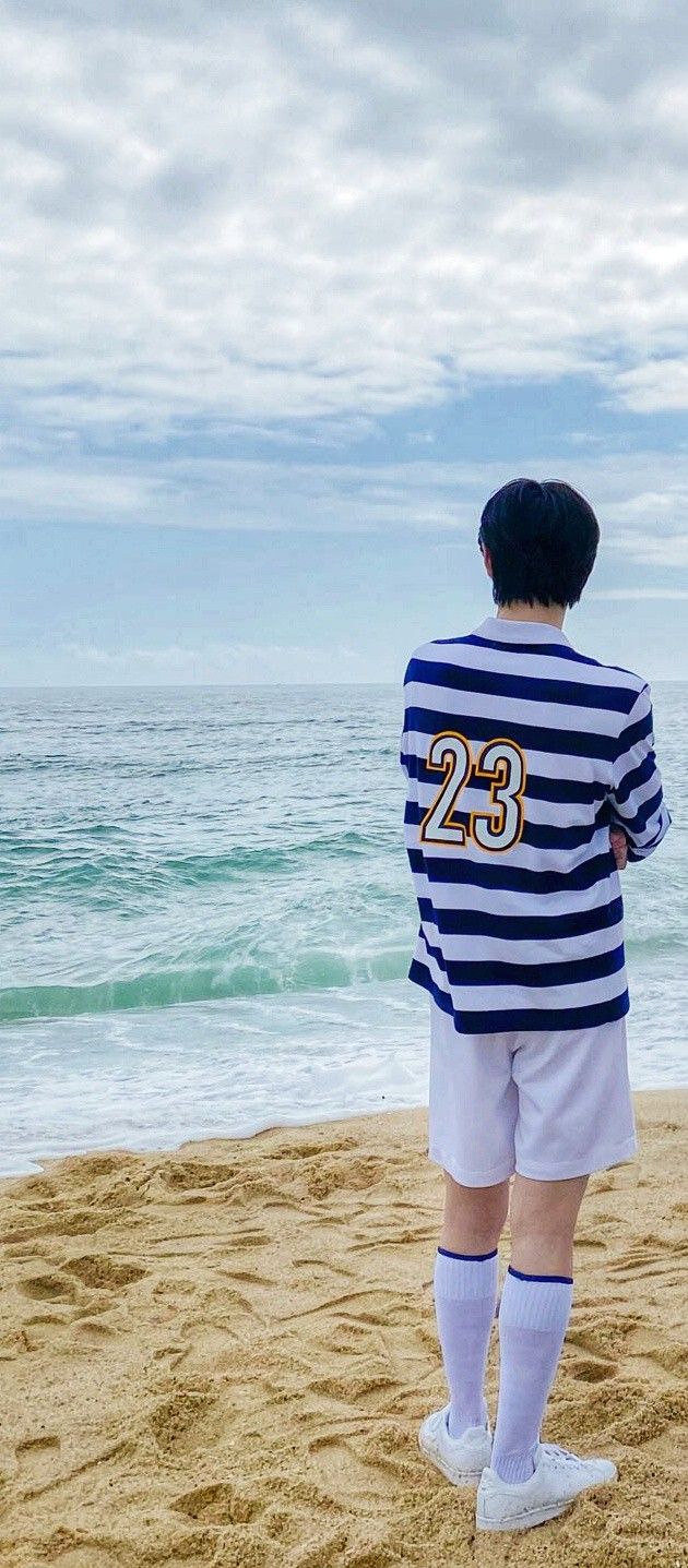 a young boy standing on top of a sandy beach