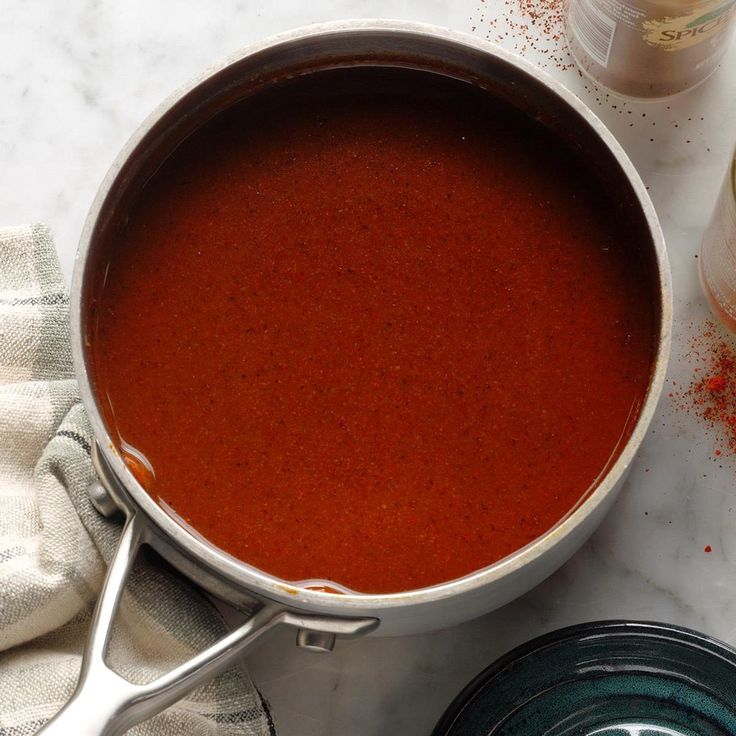 a pot filled with red liquid next to some spices