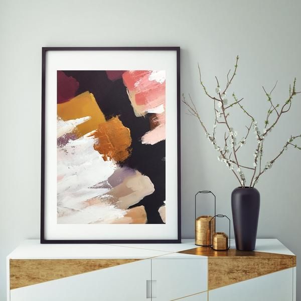 an abstract painting is displayed on the wall next to a vase with flowers in it