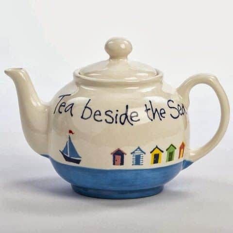 a tea pot with the words tea beside it and a sailboat painted on it