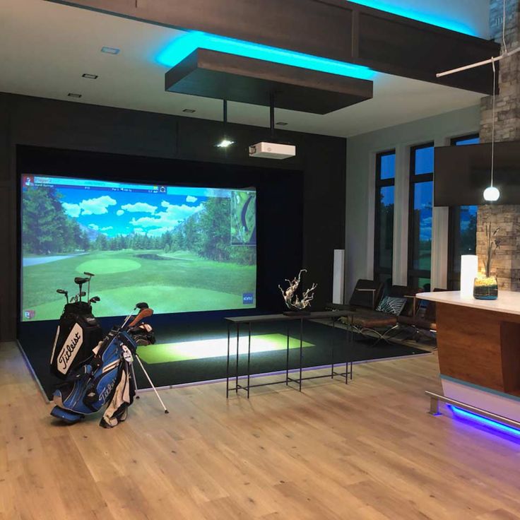 a golf simulator is set up in the middle of a large room with wooden floors