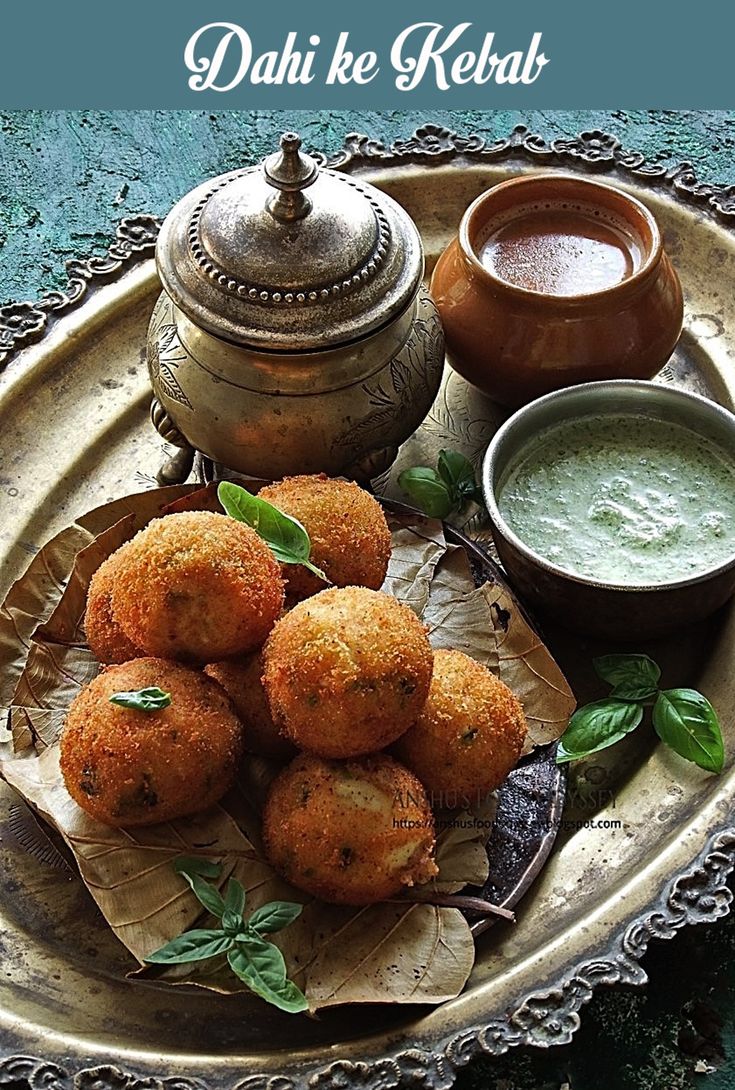 some food is sitting on a plate with sauces and a teapot in the background