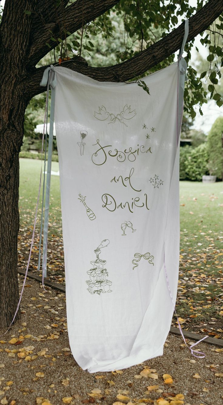 a white banner hanging from a tree with writing on it