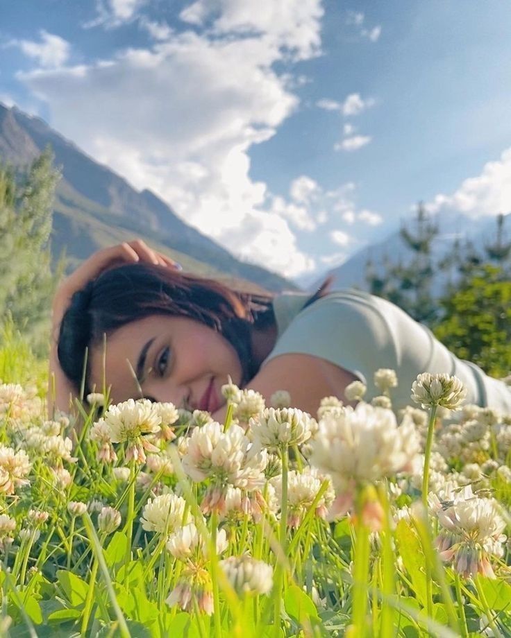 a woman laying in the grass with flowers